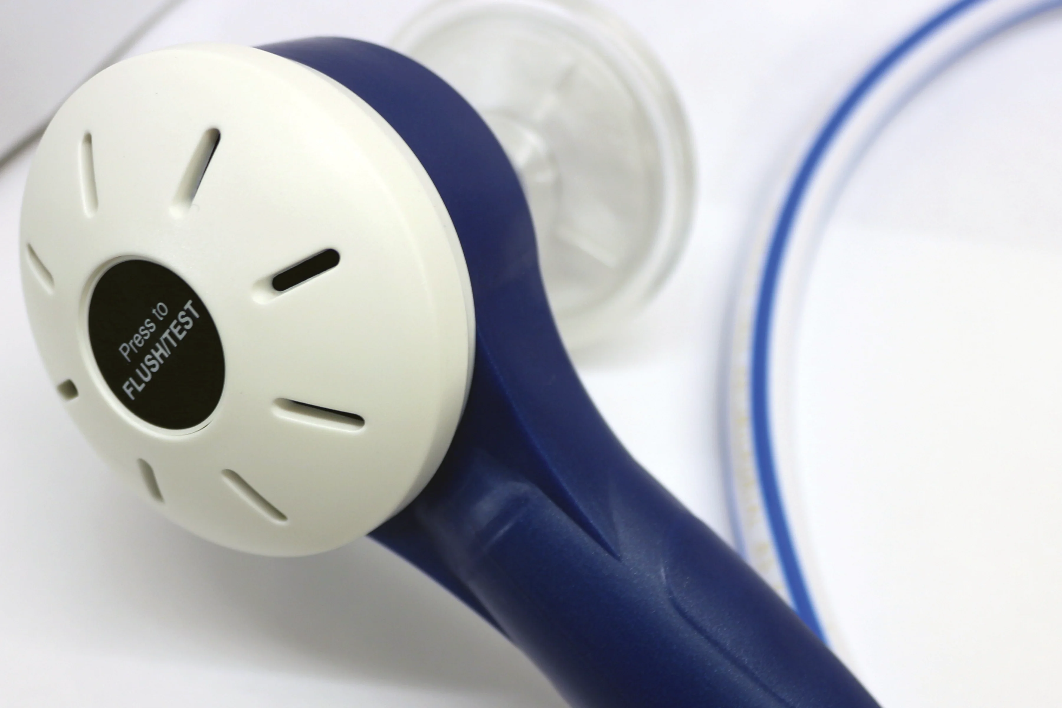 Close-up of the blue and white head of an Oxylitre demand valve, showing the Press to Flush/Test button