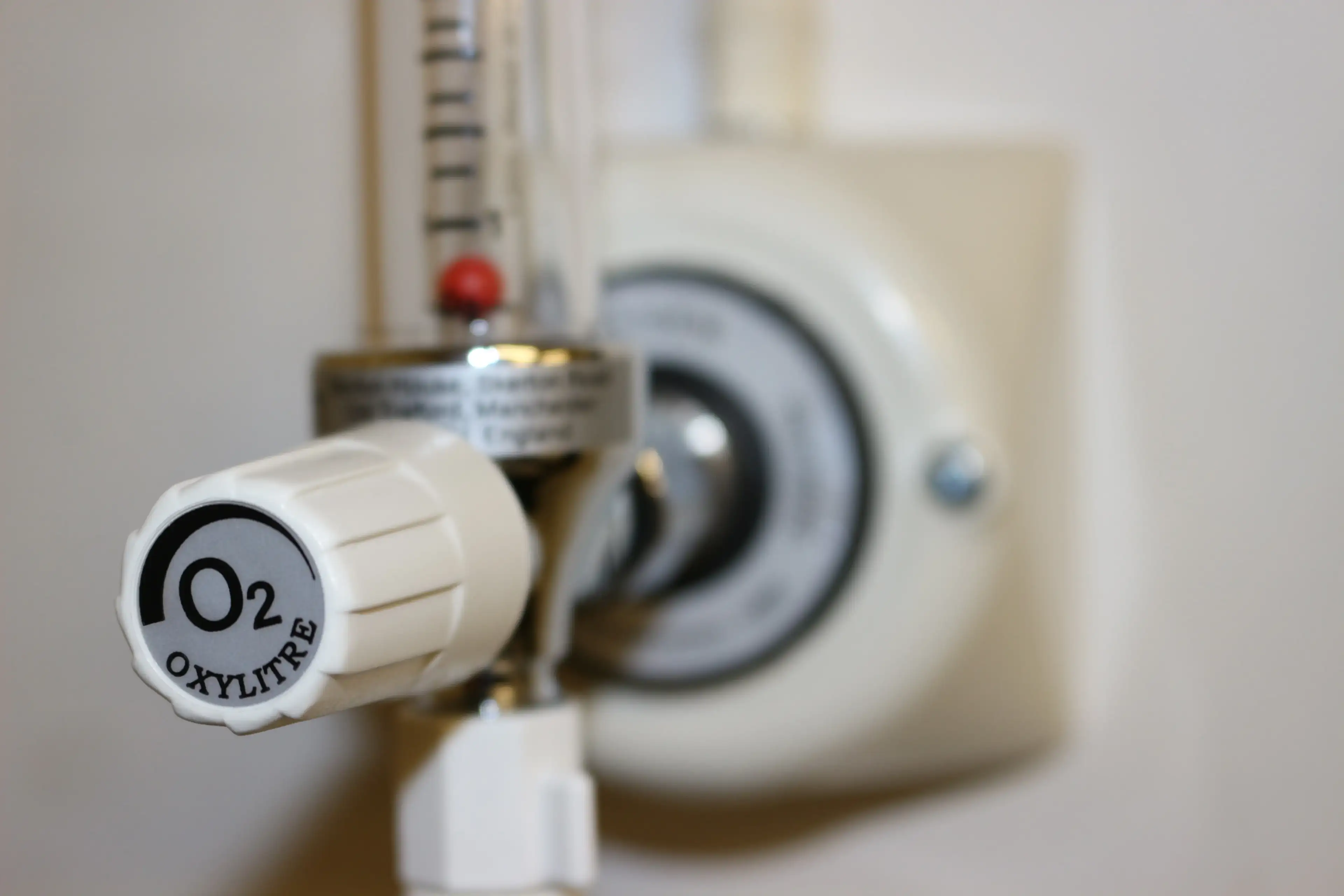 Close-up of an Oxylitre oxygen flowmeter with a white O2 control knob, fitted to a wall-mounted medical gas terminal outlet